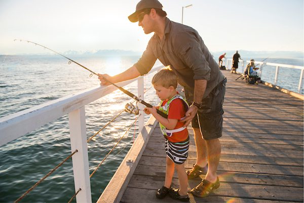 Father helping son on pier fishing Lake Tahoe